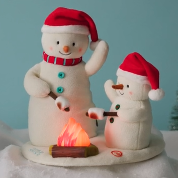 An interactive plush figure of a snowman and his son roasting marshmallows fireside.